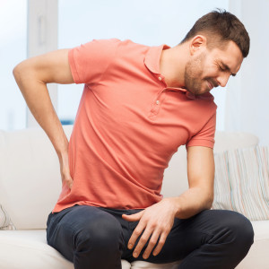 unhappy man suffering from back pain at home